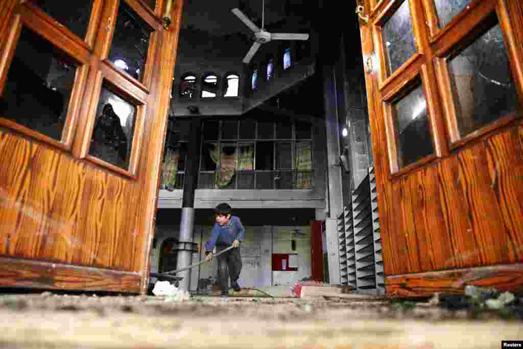 A boy cleans a damaged mosque at a site hit yesterday by an airstrike in the rebel held besieged Douma neighbourhood of Damascus, Syria.