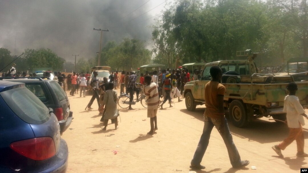 FILE - People look at smoke rising after suspected Boko Haram Islamists attack a military base in the northeast Nigerian city of Maiduguri. 
