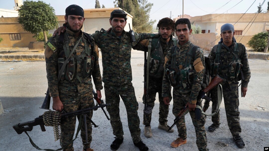 FILE - In this July 22, 2017, photo, Arab and Kurdish fighters with the U.S.-backed Syrian Democratic Forces (SDF), pose for a picture as they prepare to move to the front line to battle against the Islamic State militants, in Raqqa, northeast Syria.