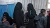 FILE - Two women, reportedly wives of IS fighters, wait with others in the internally displaced persons camp of al-Hol in al-Hasakeh governorate, Syria, Feb. 7, 2019. The United States is refusing to take back a U.S.-born IS propagandist, saying she is no longer a citizen.
