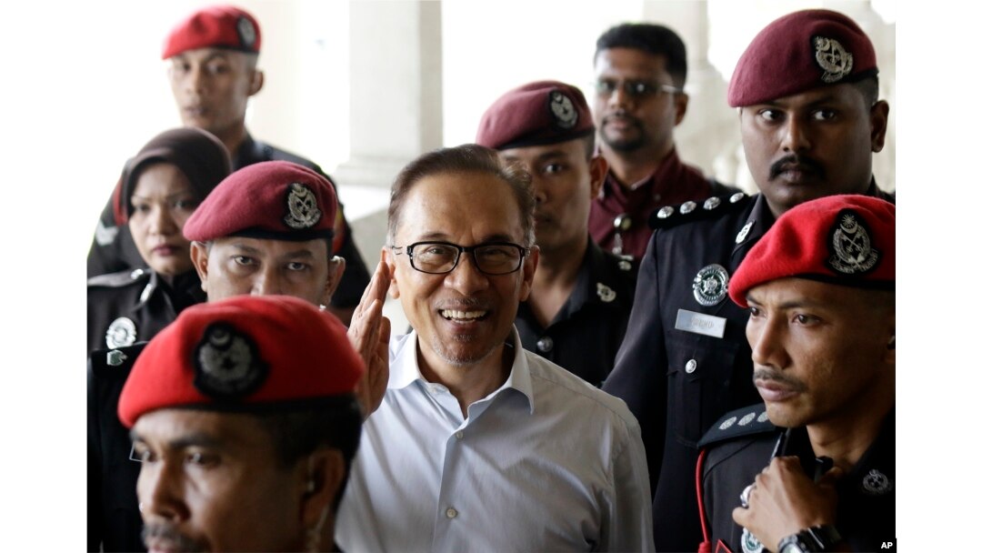 FILE - Deputy Prime Minister and opposition leader Anwar Ibrahim, center, smiles as he arrive at court house in Kuala Lumpur, Malaysia, June 13, 2017.