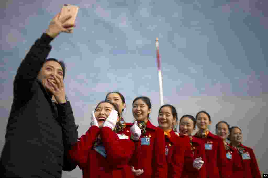 Hospitality staff members pose for a selfie during the opening session of China's National People's Congress (NPC) at the Great Hall of the People in Beijing.