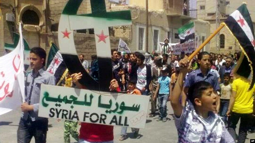 In this citizen journalism image, a protester holds up a Cross and Crescent painted with colors of the Syrian revolution flag during a demonstration against Syrian President Bashar Assad, May 18, 2012. 