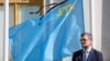 Міністр закордонних справ України Дмитро Кулеба перед прапором кримськотатарського народу з чорною стрічкою під час церемонії вшанування пам’яті жертв масової депортації кримських татар у 1944 році. Київ, Україна, 17 травня, 2024. REUTERS
