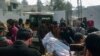 Police officers move the body of a colleague who was killed in an attack on a police station, at a hospital in Dera Ismail Khan, Pakistan, on Feb. 5, 2024.