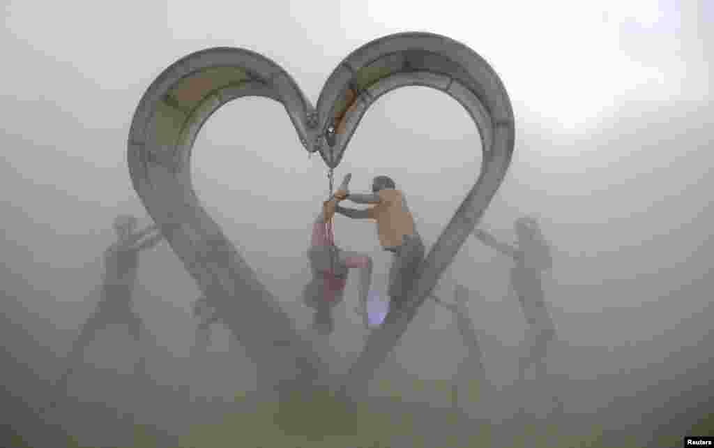 Burning Man participants perform a shibari rope scene during a desert dust storm inside the heart of the "Identity Awareness - Family" art project created by artist Shane Pitzer on the 2nd day of the annual Burning Man arts and music festival in the Black Rock Desert of Nevada, Aug. 29, 2017.