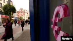 FILE - A sign displaying the euro symbol is seen on a shop window in Dublin, Oct. 22, 2014. 