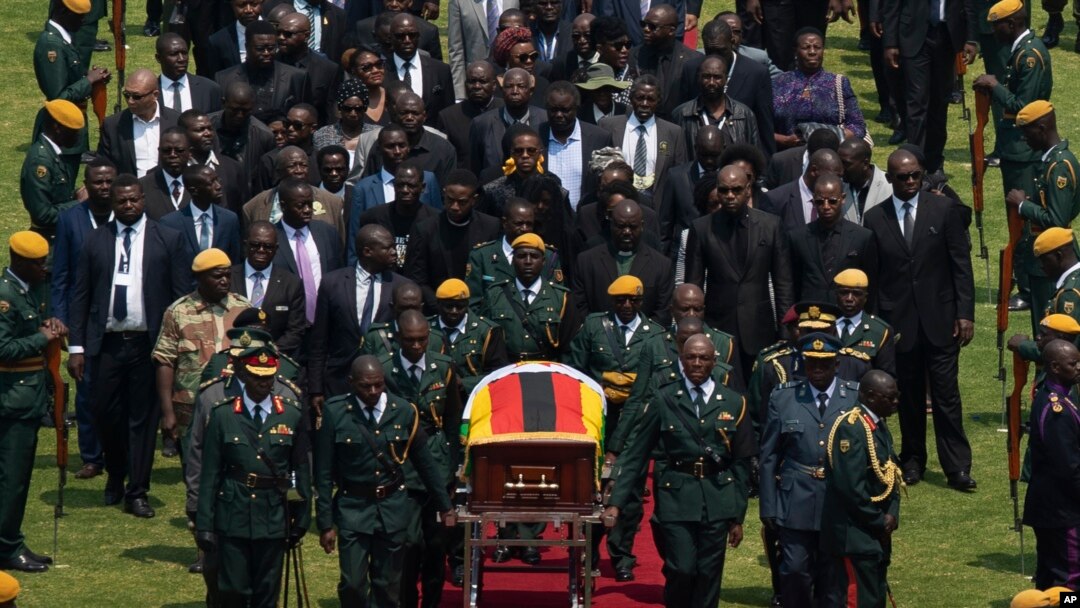 The casket of former Zimbabwean president Robert Mugabe, covered by the national flag and followed by family and dignitaries, arrives for a state funeral at the National Sports Stadium, in the capital Harare, Zimbabwe, Sept. 14, 2019.