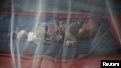 FILE - A child rests under a mosquito net in Marka's main hospital in Somalia, December 18, 2012.