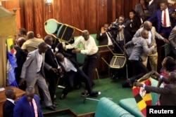 FILE - Ugandan opposition lawmakers fight with plain-clothes security personnel in the parliament while protesting a proposed age limit amendment to the constitution for the extension of the president's rule, in Kampala, Uganda, Sept. 27, 2017.