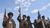 FILE - Afghan militia men raise their weapons as they stand guard in the Achin district of Nangarhar province east of Kabul, Afghanistan.