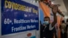 An Indian man waves to the camera before receiving his third dose of vaccination for COVID-19 at a government hospital in Gauhati, India, Jan. 10, 2022. 