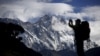 FILE - A tourist is silhouetted as he takes pictures of Mount Nuptse, center, as Mount Everest, left, is covered with clouds in Solukhumbu district, also known as the Everest region, Nov. 30, 2015.