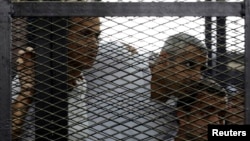 FILE - From left, Peter Greste, Mohamed Fahmy and Baher Mohamed listen to the ruling at a court in Cairo, Egypt.