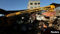 Les Palestiniens inspectent la scène de ce que les témoins ont dit etre une attaque aérienne sur un atelier dans la ville de Gaza , le 5 mai 2016 .