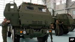 Польські солдати роздивляються вантажівку, яка перевозить американську ракетну систему залпового вогню HIMARS, на авіабазі у Варшаві, 15 травня 2023 р. (Фото: AP Photo/Czarek Sokolowski)