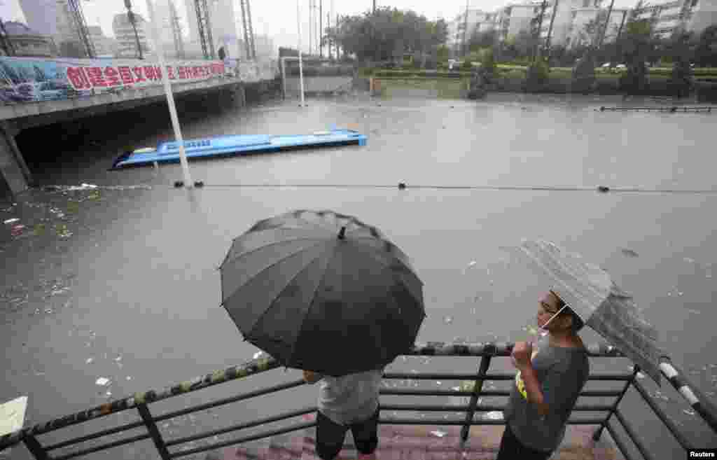 Residents look at a submerged bus on a flooded street in the Tianjin municipality, China, July 26, 2012.
