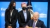 U.S. Women's National Soccer Team players Margaret Purce and Megan Rapinoe peek over U.S. President Joe Biden’s shoulder as he signs an Equal Pay Day proclamation at the White House in Washington, March 24, 2021. 