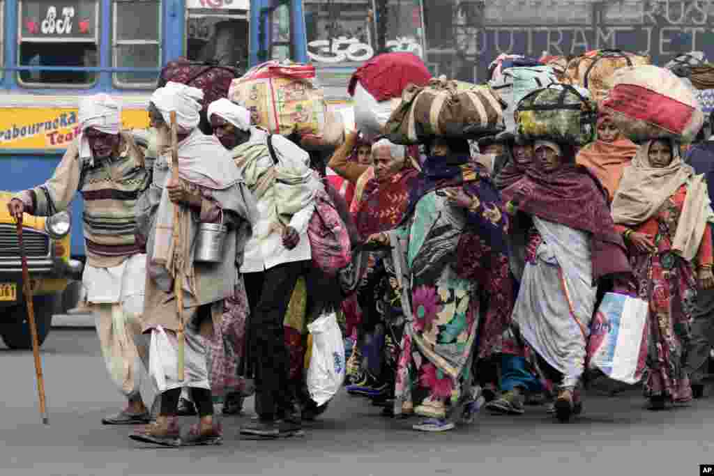 Pilgrims cross a busy road after taking a holy dip at Hooghly River on the auspicious Makar Sankranti festival day, in Kolkata, India.