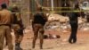 FILE - Burkina Faso security force personnel stand next to the body of a suspected jihadist in Ouagadougou, May 22, 2018, after a pre-dawn raid by security forces on a house in the capital of Burkina Faso.
