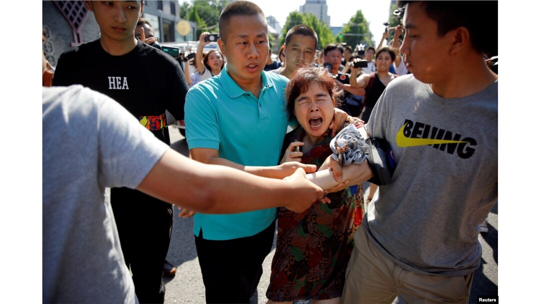 A woman is detained by security personnel outside the U.S. embassy in Beijing, China, July 26, 2018.