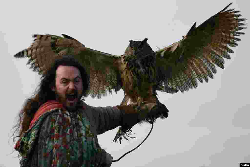 Druid Malachy, played by Ciaron Davies, reacts with a European eagle-owl named 'Cracker' during the re-enactment of the first landing of Saint Patrick in Ireland at Inch Abbey in Downpatrick, Northern Ireland, March 11, 2018.