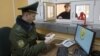 FILE - A Belarussian border guard checks a tourist's passport at a border crossing with Poland, near the village of Pererov, southwest of Minsk, March 31, 2015.