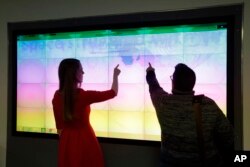 Connecticut College digital scholarship librarian Lyndsay Bratton, left, and assistant professor in Gender and Women's studies Ariella Rotramel, right, use the visualization wall at the Charles E. Shain Library in New London, May 3, 2016.