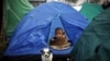 A boy sits inside a tent on an open ground, after Saturday's earthquake in Kathmandu, Nepal early April 29, 2015. 