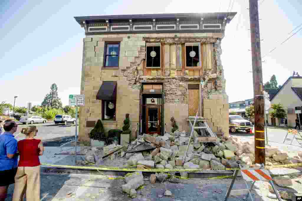 Pedestrians stop to examine a crumbling facade at the Vintner's Collective tasting room in Napa, California, following an earthquake, Aug. 24, 2014.