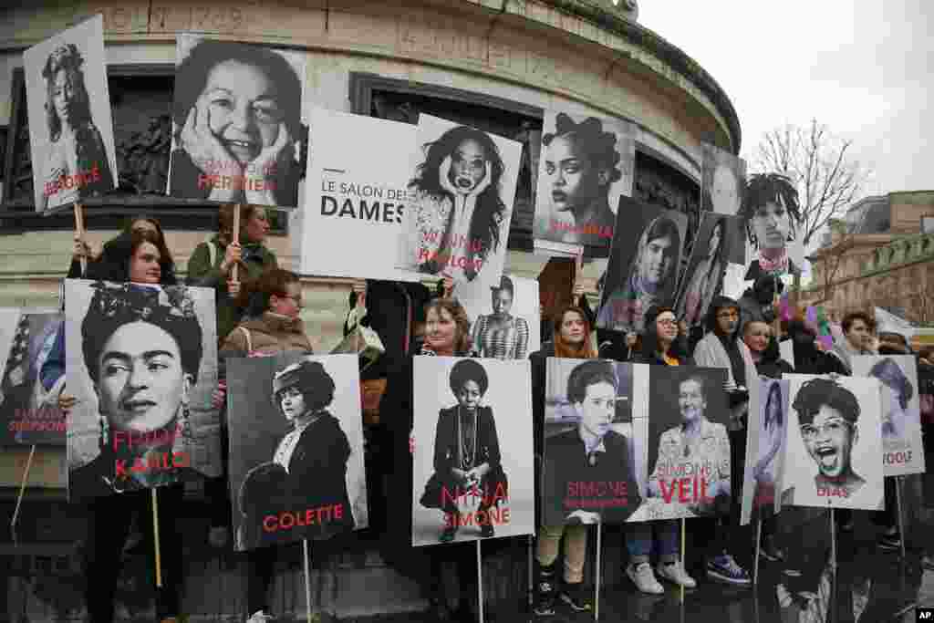 Women hold posters of famous feminists during a gathering to mark International Women's Day in Paris, France.