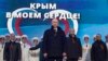 FILE - Russian President Vladimir Putin, with leaders of newly annexed Crimea in the background, is seen at a rally in Moscow, March 18, 2014. 