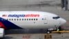 Ground staff take a break under a Malaysia Airlines plane at Kuala Lumpur International Airport in Sepang, Malaysia, March 9, 2014.