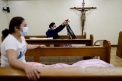 FILE - Hospital workers wearing protective masks prepare to sleep on pews at a funeral chapel that serves as a temporarily shelter for them amid the coronavirus spread, in Makati City, Metro Manila, Philippines, April 1, 2020.
