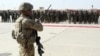FILE - In this July 24, 2016 file photo, a U.S. military personal stands guard during a graduation ceremony for Afghan troops, in Lashkargah, capital of southern Helmand province, Afghanistan. 