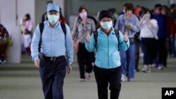 A passenger wearing a mask gestures as they arrive at Manila's international airport, Philippines, Thursday, Jan. 23, 2020.