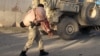 FILE - An Afghan security personnel carries a wounded man after a suicide car bomb blast attacked a military convoy in Lashkar Gah, Helmand province, Afghanistan, Nov. 15, 2015.