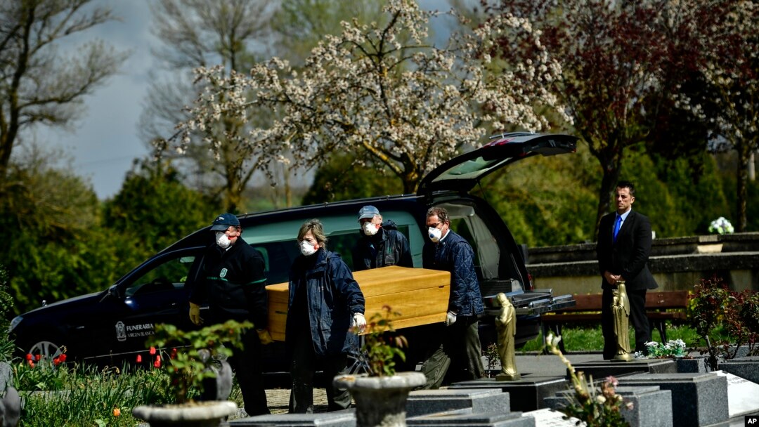 Undertakers wearing protection masks to protect from the coronavirus, carry a coffin to a burial at Salvador cemetery during the coronavirus outbreak, near to Vitoria, northern Spain, Monday, March 30, 2020. 