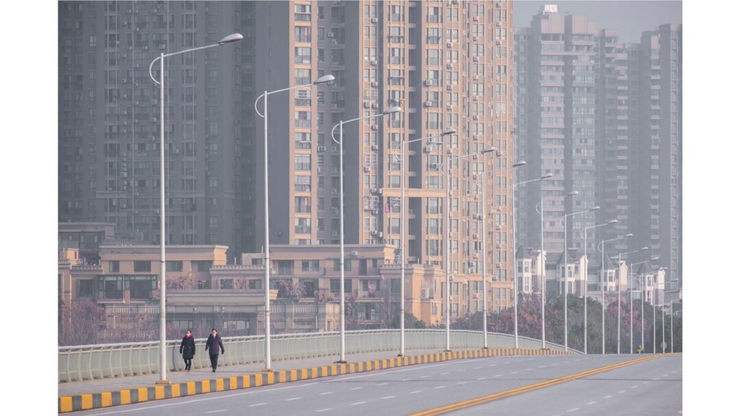 People wearing face masks walk down a deserted street in Wuhan in central China's Hubei Province, Jan. 28, 2020.