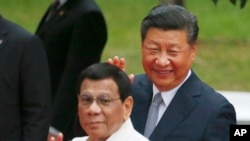 FILE - Chinese President Xi Jinping and Philippine President Rodrigo Duterte wave to the media following a welcome ceremony at Malacanang Palace in Manila, Philippines, Nov. 20, 2018. 
