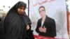 FILE - A women walks past electoral posters of Louisa Hanoune, a candidate for Algeria's Workers' Party in the 2014 presidential election, March 27, 2014.