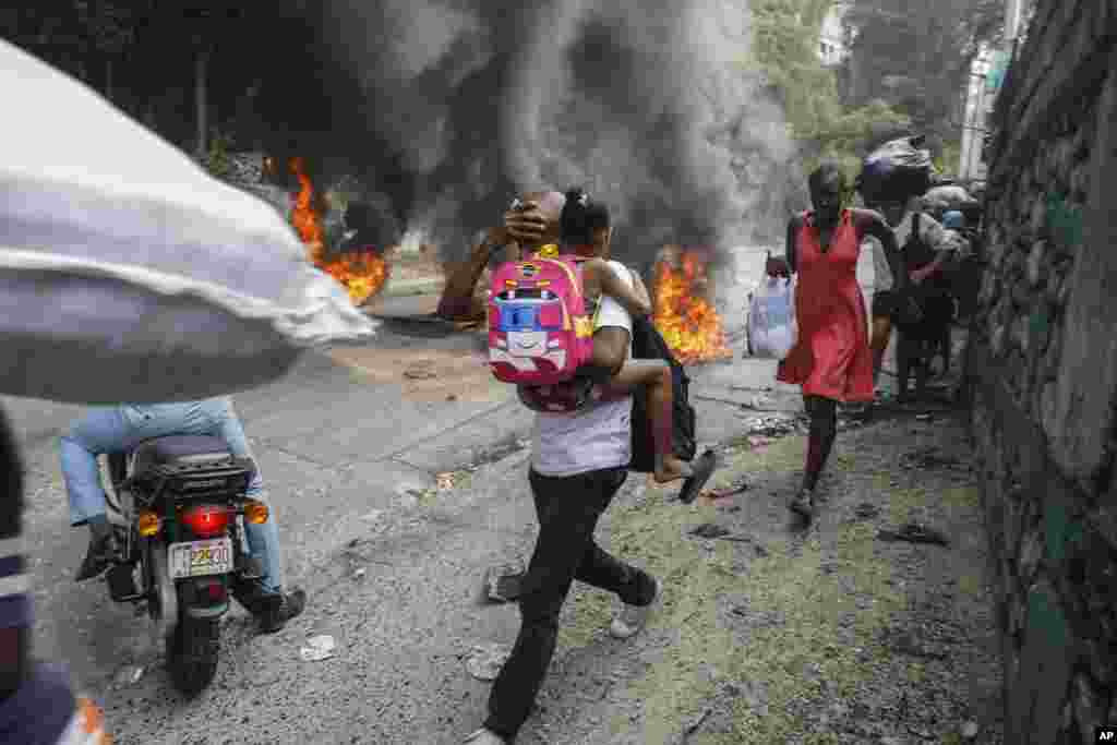 People walk past burning tires during a protest against Haitian Prime Minister Ariel Henry in Port-au-Prince, Feb. 5, 2024. Banks, schools and government agencies closed in Haiti’s northern and southern regions while protesters blocked main routes with blazing tires and paralyzed public transportation, according to local media reports.