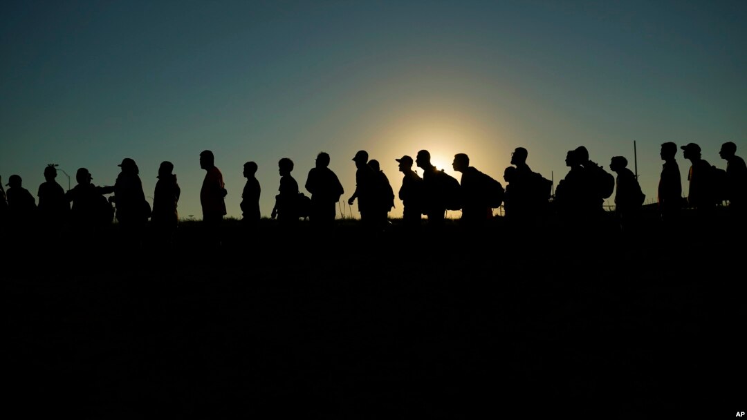 FILE - Migrants who crossed the Rio Grande from Mexico line up for processing by U.S. Customs and Border Protection, Sept. 23, 2023, in Eagle Pass, Texas. The White House announced on May 16, 2024, a plan to cut the time some migrants wait to find out whether they get asylum.