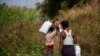 FILE - Myanmar refugees, who fled a surge in violence as the military cracks down on rebel groups, walk with food aid on the Thai border in Thailand's Mae Sot district, Jan. 15, 2022.