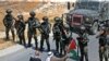 Palestinian protesters sit before Israeli troops during a demonstration against the expropriation of Palestinian land by Israel, in the village of Kafr Malik northeast of Ramallah in the Israeli-occupied West Bank.