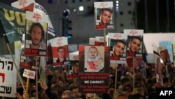 Relatives and supporters hold placards bearing portraits of Israeli hostages held in Gaza since the October 7 attacks by Hamas in southern Israel, during a rally calling for their release and marking their nearly 100 days of captivity, in Tel Aviv on Janu