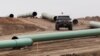 FILE - A vehicle drives next to a series of pipes at a Dakota Access construction site near the town of Cannon Ball, North Dakota, Oct. 30, 2016.