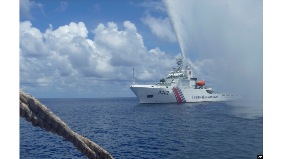 FILE - Chinese Coast Guard members approach Filipino fishermen as they confront each other off Scarborough Shoal in the South China Sea, also called the West Philippine Sea, Sept. 23, 2015.