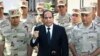 In this photo provided by MENA news agency, Egyptian President Abdel-Fattah el-Sissi speaks in front of the state-run TV ahead of a military funeral for troops killed in an assault in the Sinai Peninsula, as he stands with army commanders in Cairo, Oct. 25, 2014.