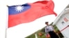 FILE - A Taiwan Coast Guard officer stands guard under a Taiwanese flag in the East China Sea, north of Taiwan, April 9, 2016.